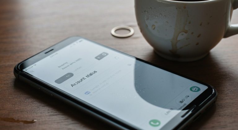 How to Get Unbanned from Amazon Flex (Proven Fix) 4 A smartphone showing an account status notification on a desk with a coffee mug, focusing on the screen and surface details.