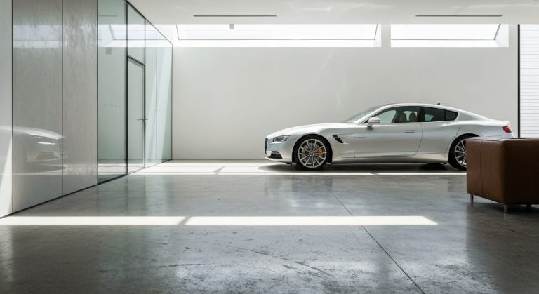 Interior of a modern luxury car condo with polished concrete floors, architectural lighting, and a silver sports car.